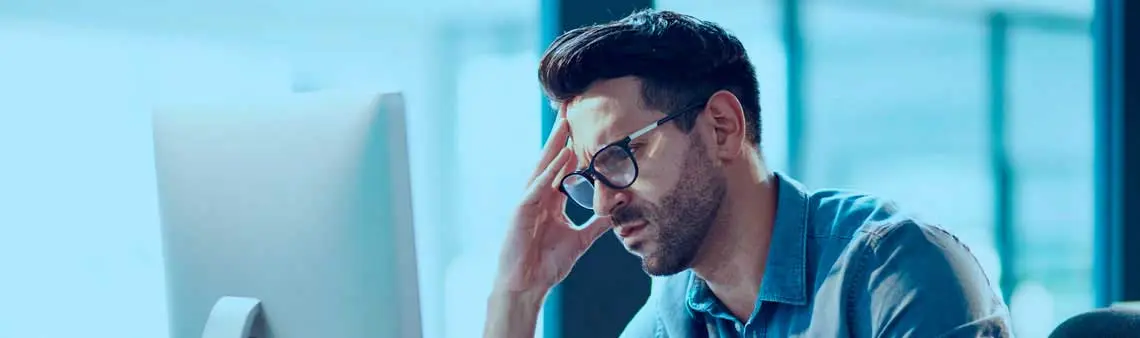 Homem frustrado na frente do computador no ambiente de trabalho