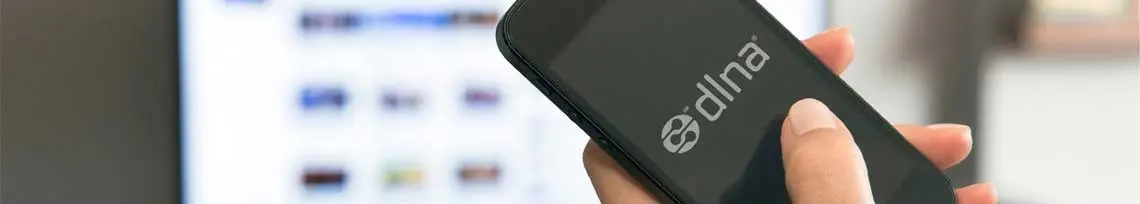 Mulher com smartphone na mão com logo do DLNA na tela e uma TV ao fundo